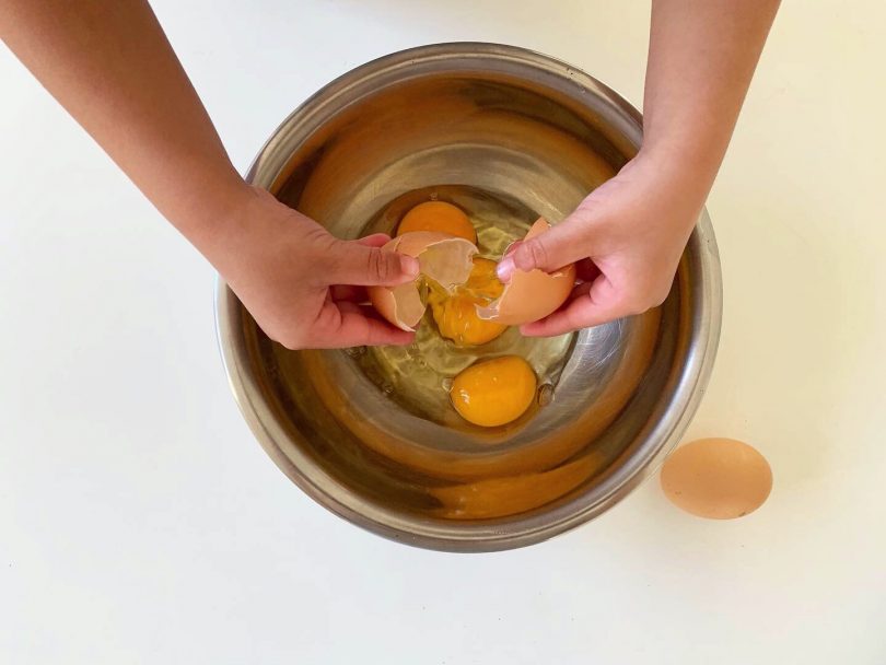 les enfants cassent les oeufs pour ce gâteau jardinière